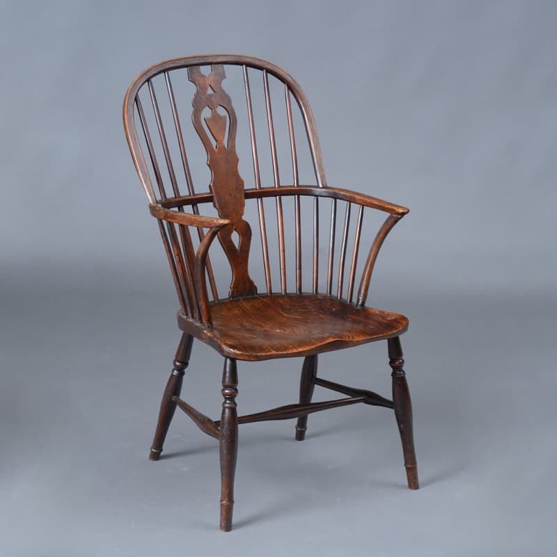 A Windsor chair with splayed legs socketed into a solid seat, spindles and splat rising from above